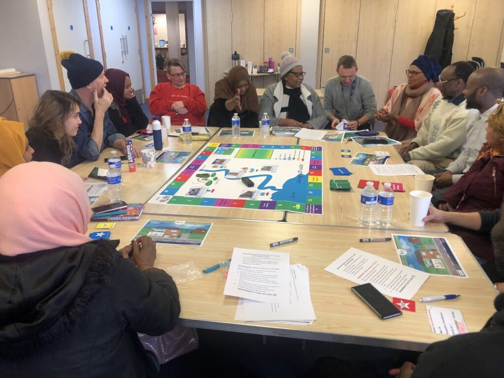Community participants seated around a table playing the Just Flood Resilience Co-op serious game to discuss urban flood risk and governance.